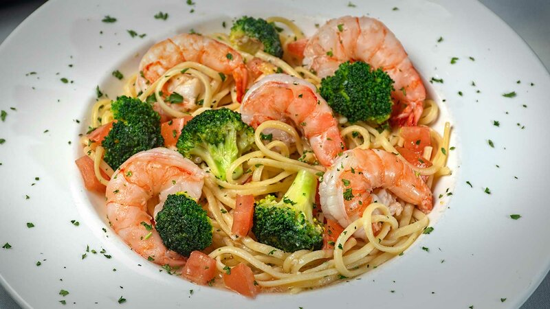 Close up view of shrimp with broccoli over pasta